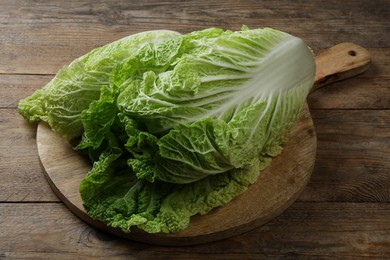 Photo of Cutting board with fresh ripe Chinese cabbage on wooden table, closeup