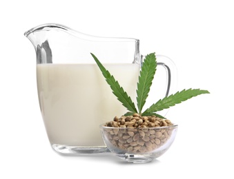 Photo of Bowl with hemp seeds and jug of milk on white background