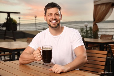 Photo of Man with glass of dark beer in outdoor cafe