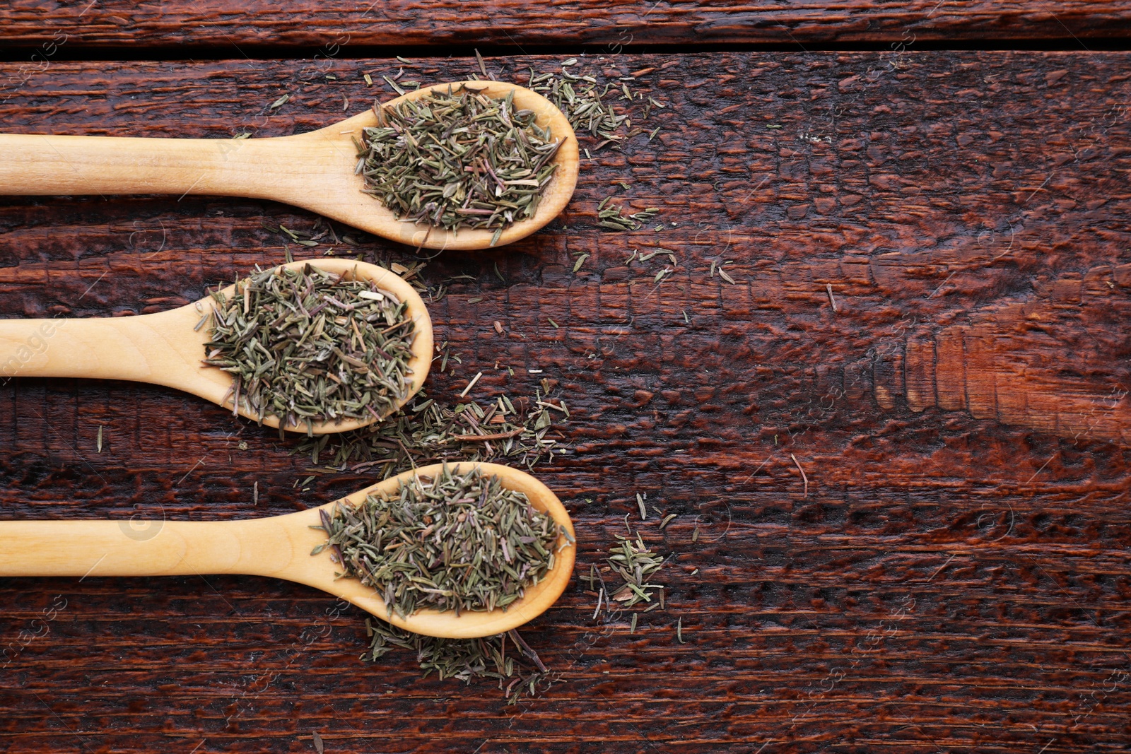 Photo of Spoons with dried thyme on wooden table, flat lay. Space for text