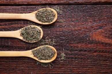 Photo of Spoons with dried thyme on wooden table, flat lay. Space for text