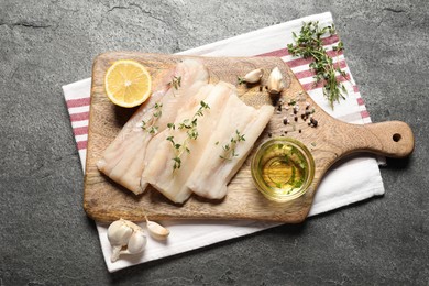 Photo of Raw cod fish, microgreens, lemon, spices and oil on grey textured table, top view