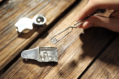 Male jeweler evaluating precious gemstone at table in workshop, closeup