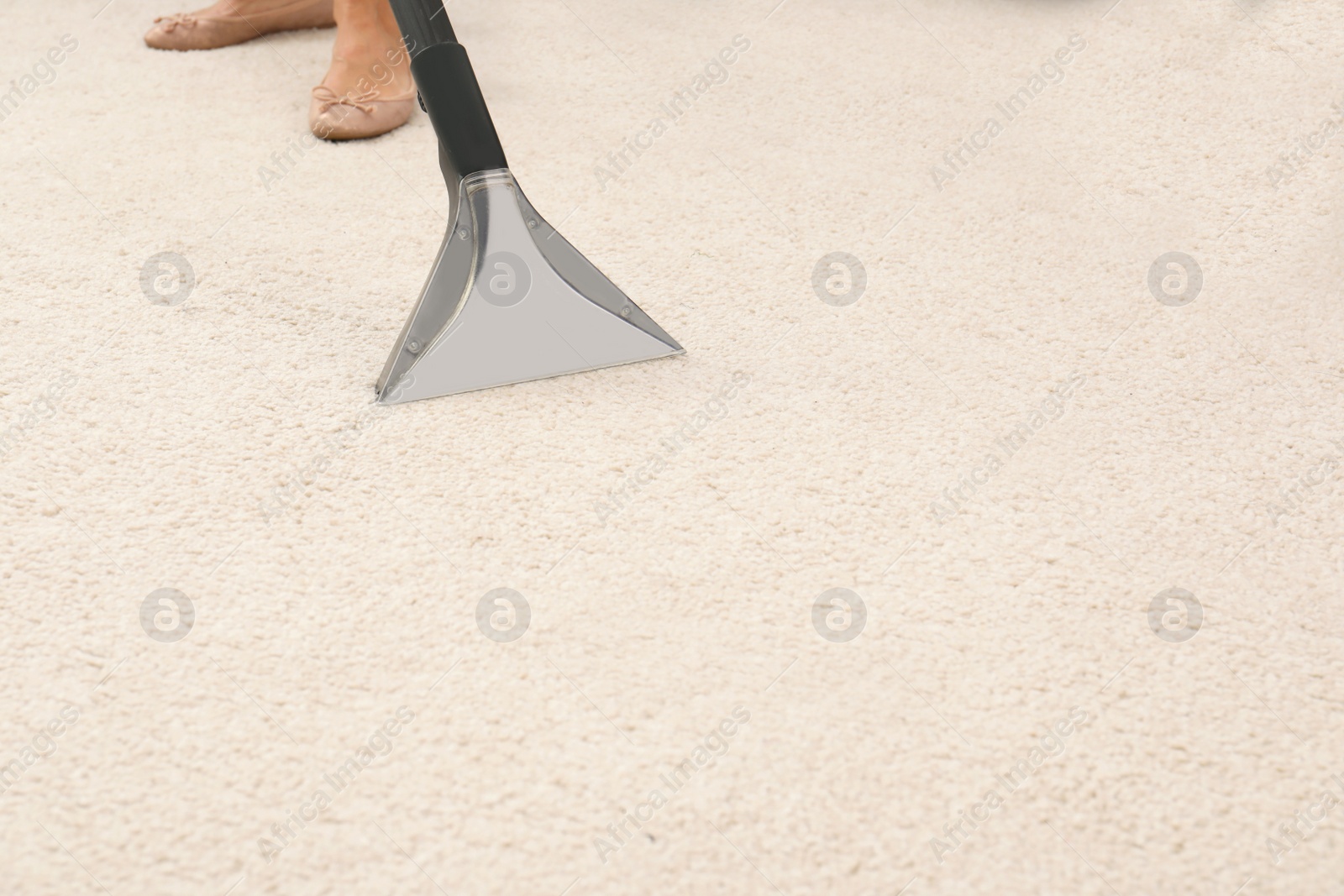 Photo of Woman removing dirt from carpet with vacuum cleaner indoors, closeup. Space for text