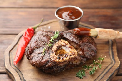 Photo of Delicious roasted beef meat served with sauce and spices on wooden table, closeup