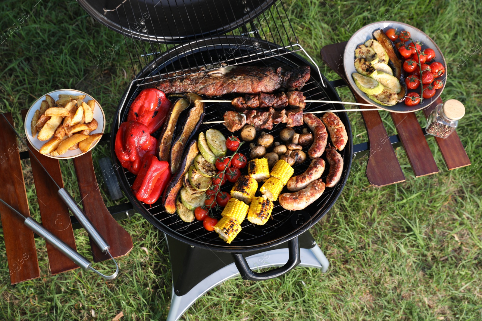 Photo of Tasty meat and vegetables on barbecue grill outdoors, top view