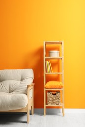 Photo of Stylish beige sofa and wooden rack near orange wall indoors. Interior design