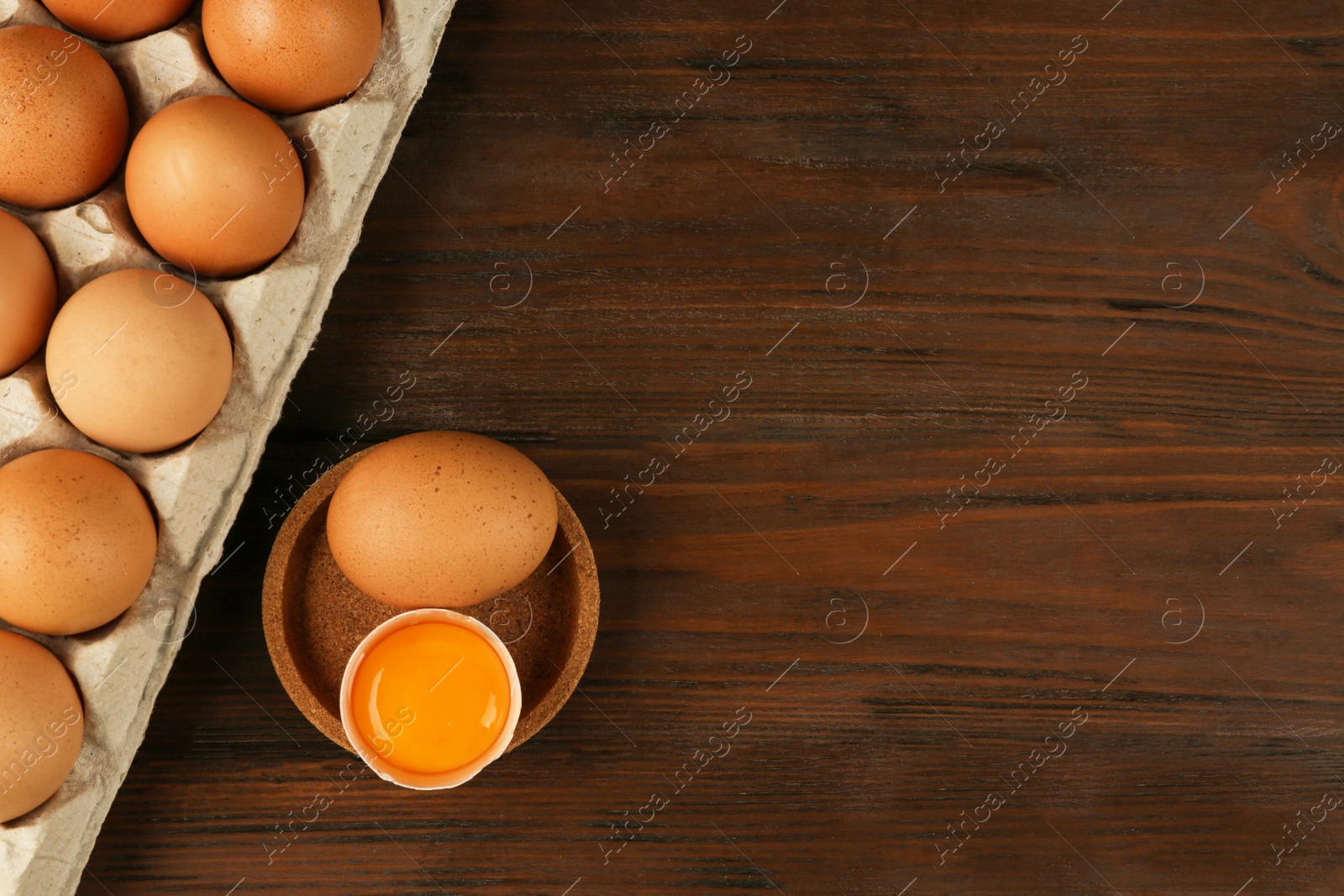 Photo of Raw chicken eggs on wooden table, flat lay. Space for text