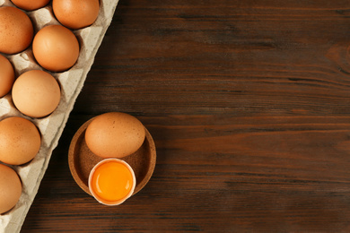 Photo of Raw chicken eggs on wooden table, flat lay. Space for text