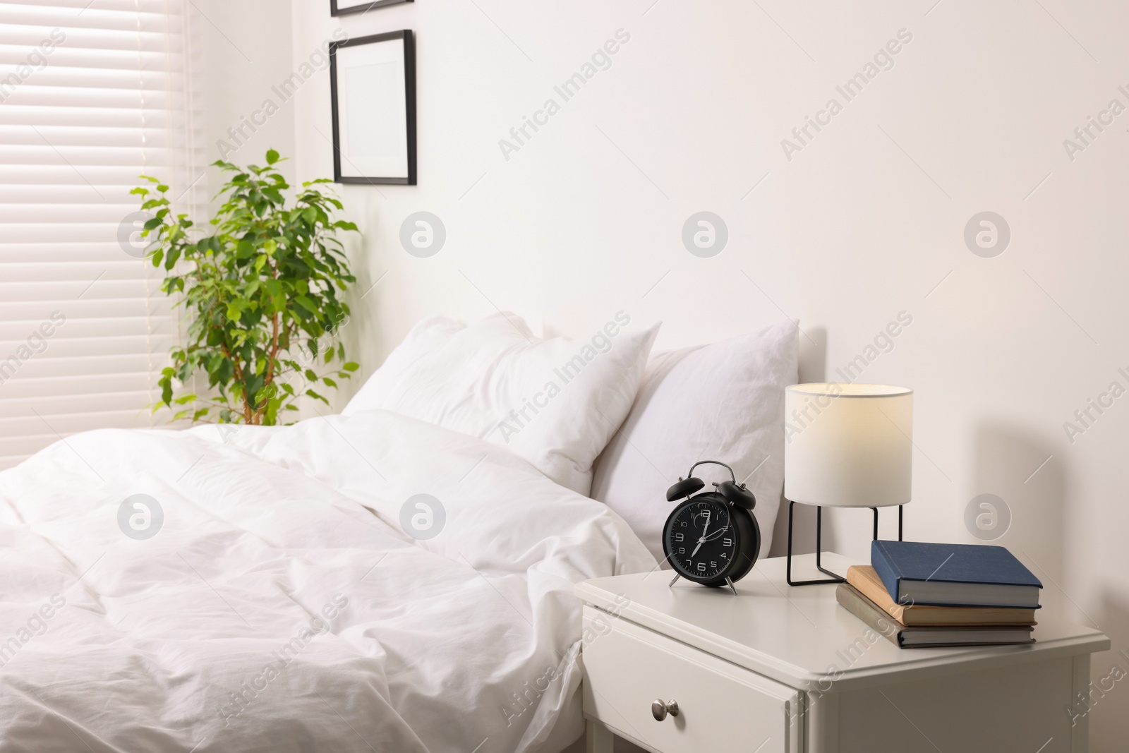 Photo of Stylish light room with comfortable bed and bedside table. Interior design