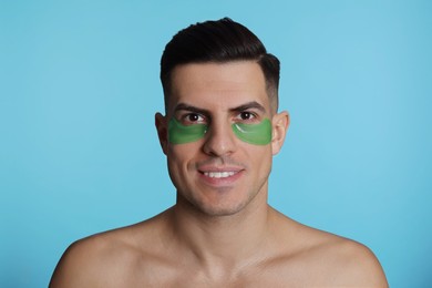 Photo of Man with green under eye patches on light blue background