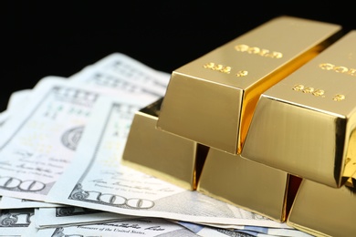 Photo of Shiny gold bars and money on black background, closeup