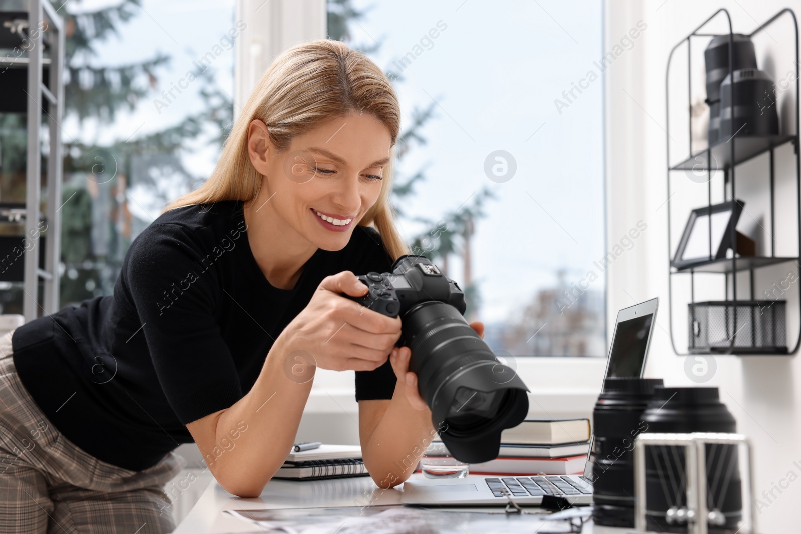 Photo of Professional photographer with digital camera at table in office