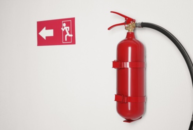 Photo of Fire extinguisher and emergency exit sign on white wall