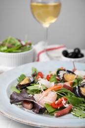 Plate of delicious salad with seafood on white tiled table, closeup
