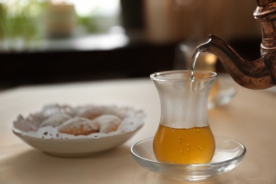 Photo of Pouring hot tea into glass cup on table