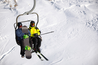 People using chairlift at mountain ski resort, space for text. Winter vacation