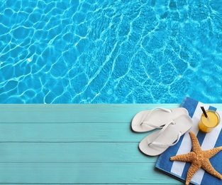 Image of Beach accessories on turquoise wooden deck near swimming pool, flat lay. Space for text 