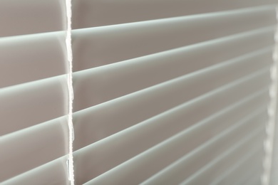 Photo of Closed modern white window blinds, closeup view