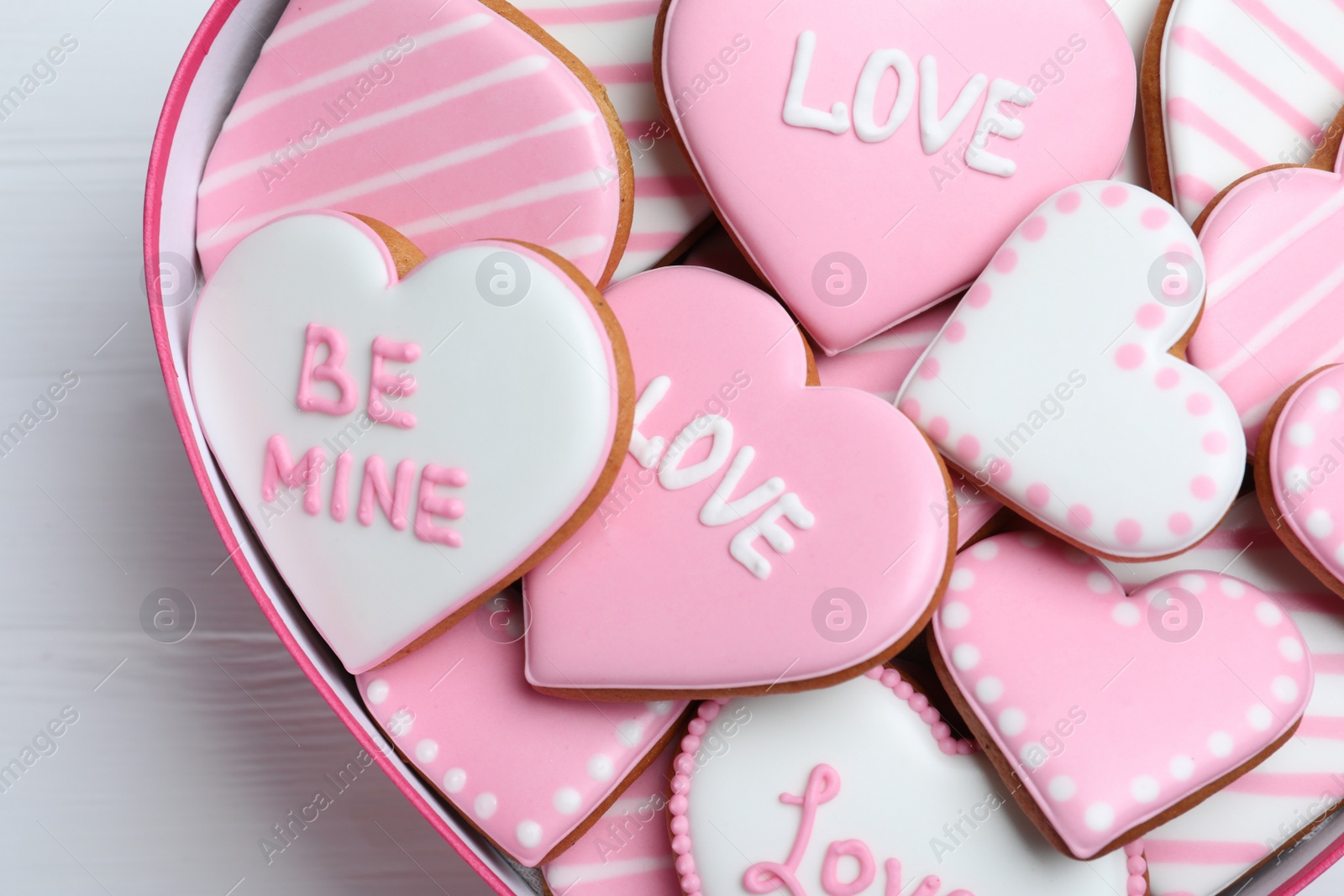 Photo of Delicious heart shaped cookies in box on white table, closeup. Valentine's Day