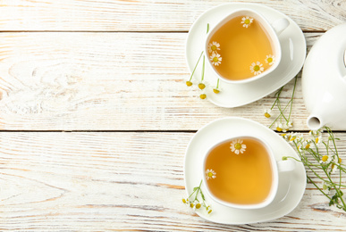 Photo of Flat lay composition with tea and chamomile flowers on white wooden table. Space for text