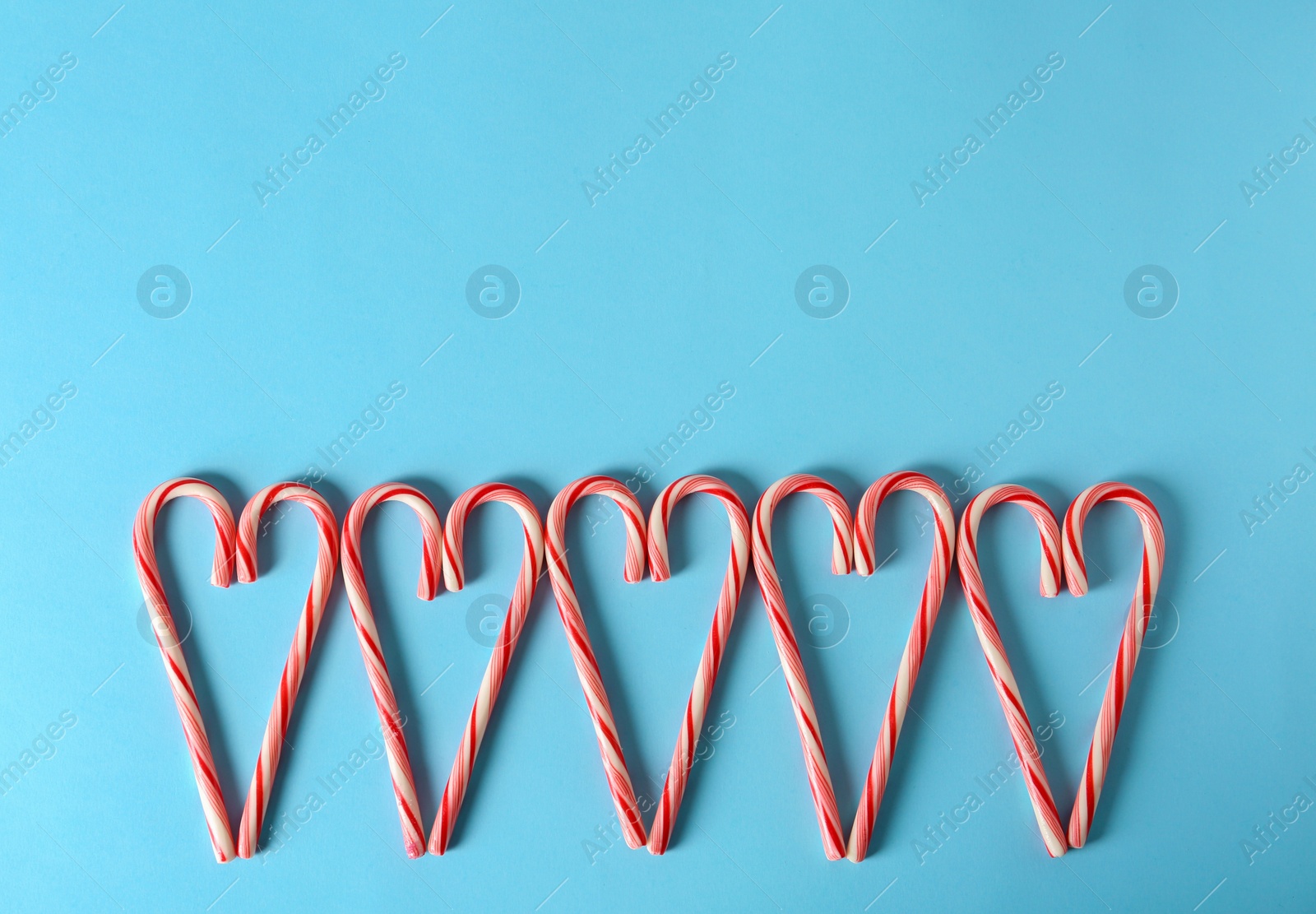 Photo of Sweet hearts made of candy canes on color background, top view with space for text