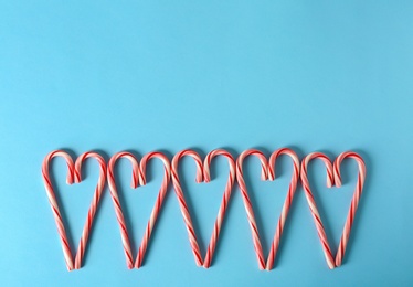 Sweet hearts made of candy canes on color background, top view with space for text