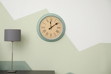 Photo of Big clock hanging on color wall. Time concept