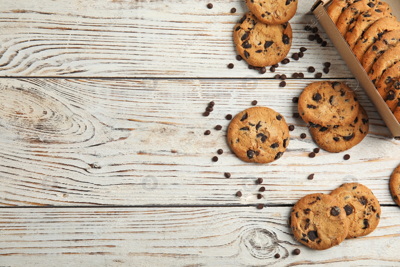 Photo of Delicious chocolate chip cookies on wooden table, flat lay. Space for text