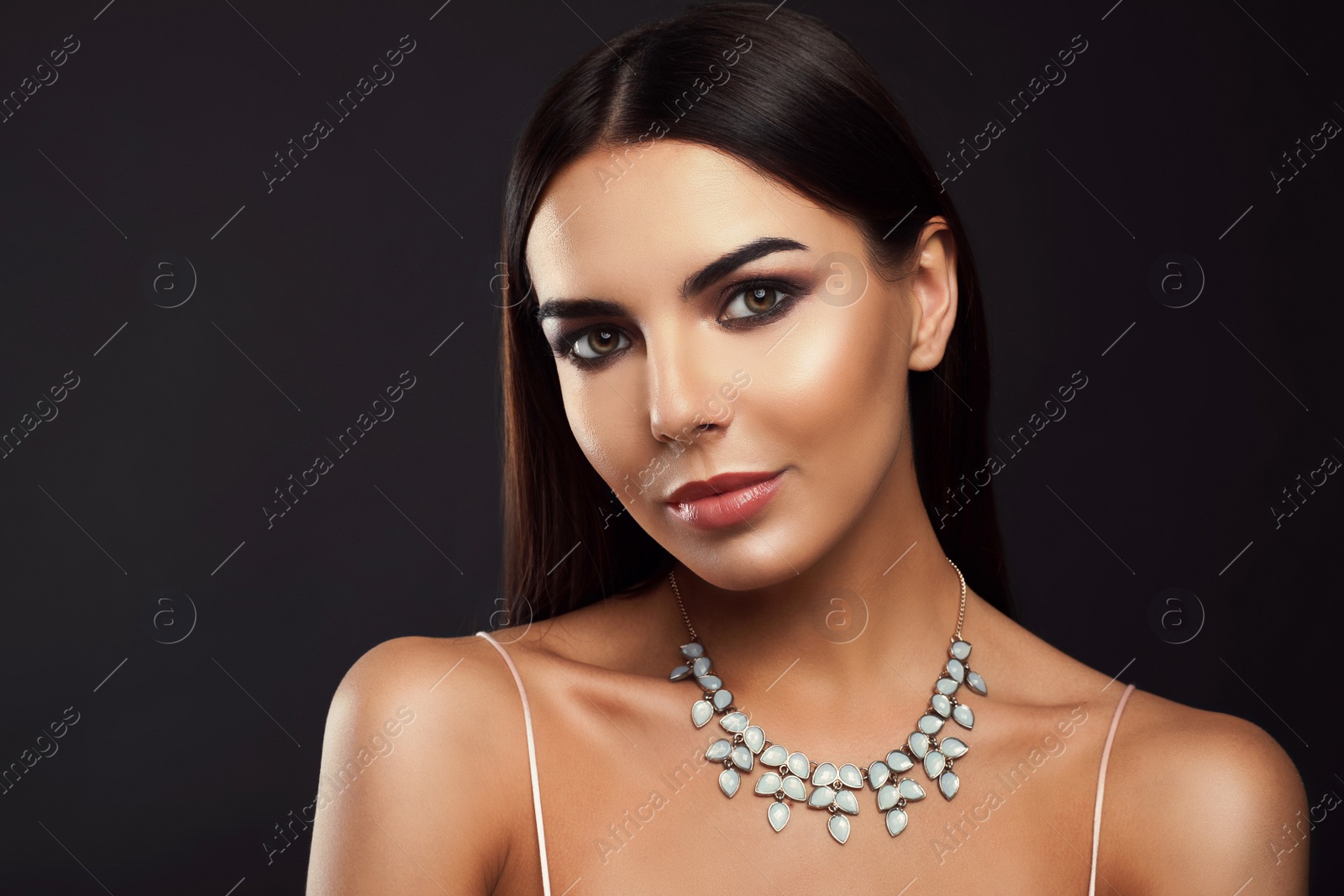 Photo of Beautiful young woman with elegant jewelry on dark background. Space for text