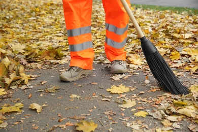 Photo of Street cleaner sweeping fallen leaves outdoors on autumn day