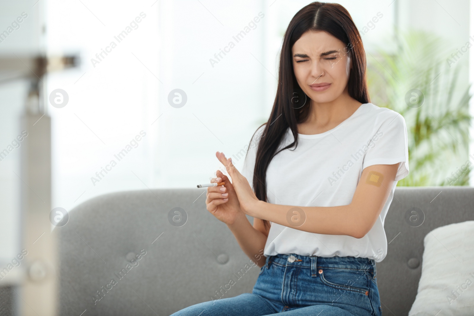 Photo of Emotional young woman with nicotine patch and cigarette at home. Space for text