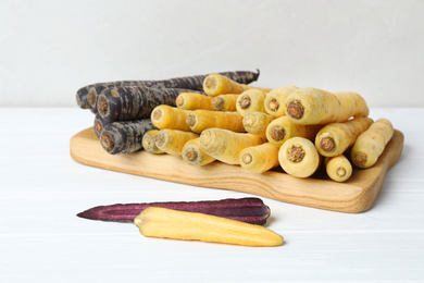 Photo of Many different raw carrots on white wooden table