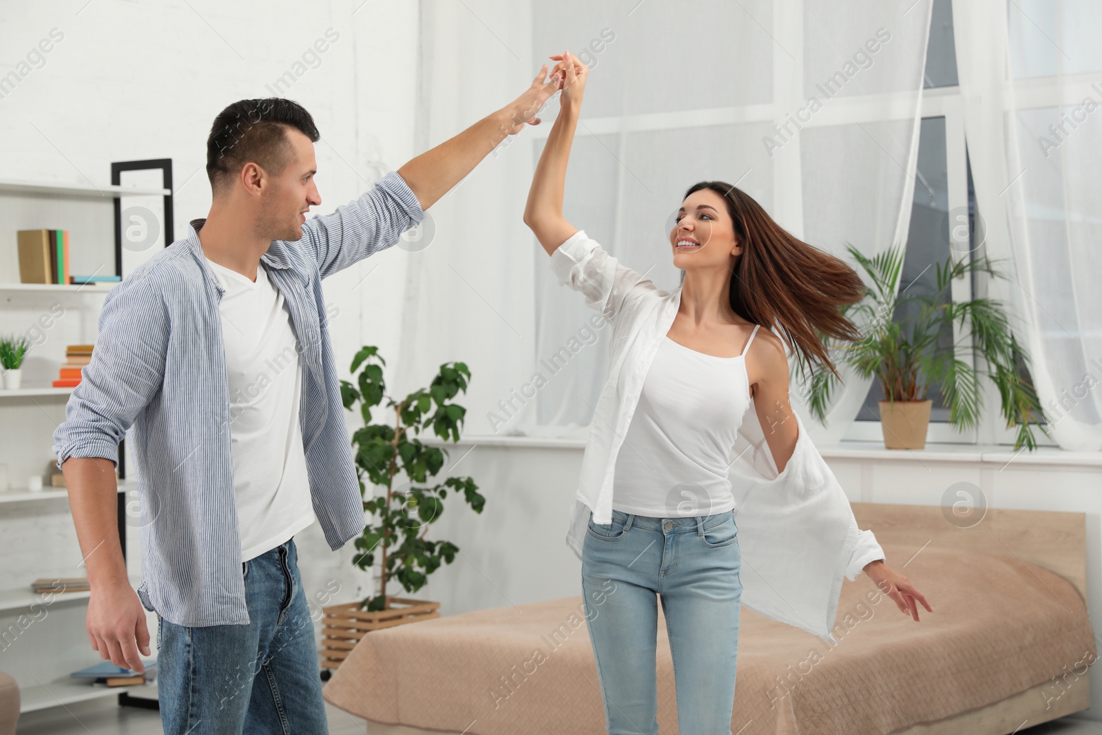 Photo of Happy couple dancing in bedroom at home