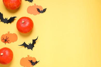 Photo of Flat lay composition with paper bats, pumpkins and spider on yellow background, space for text. Halloween decor