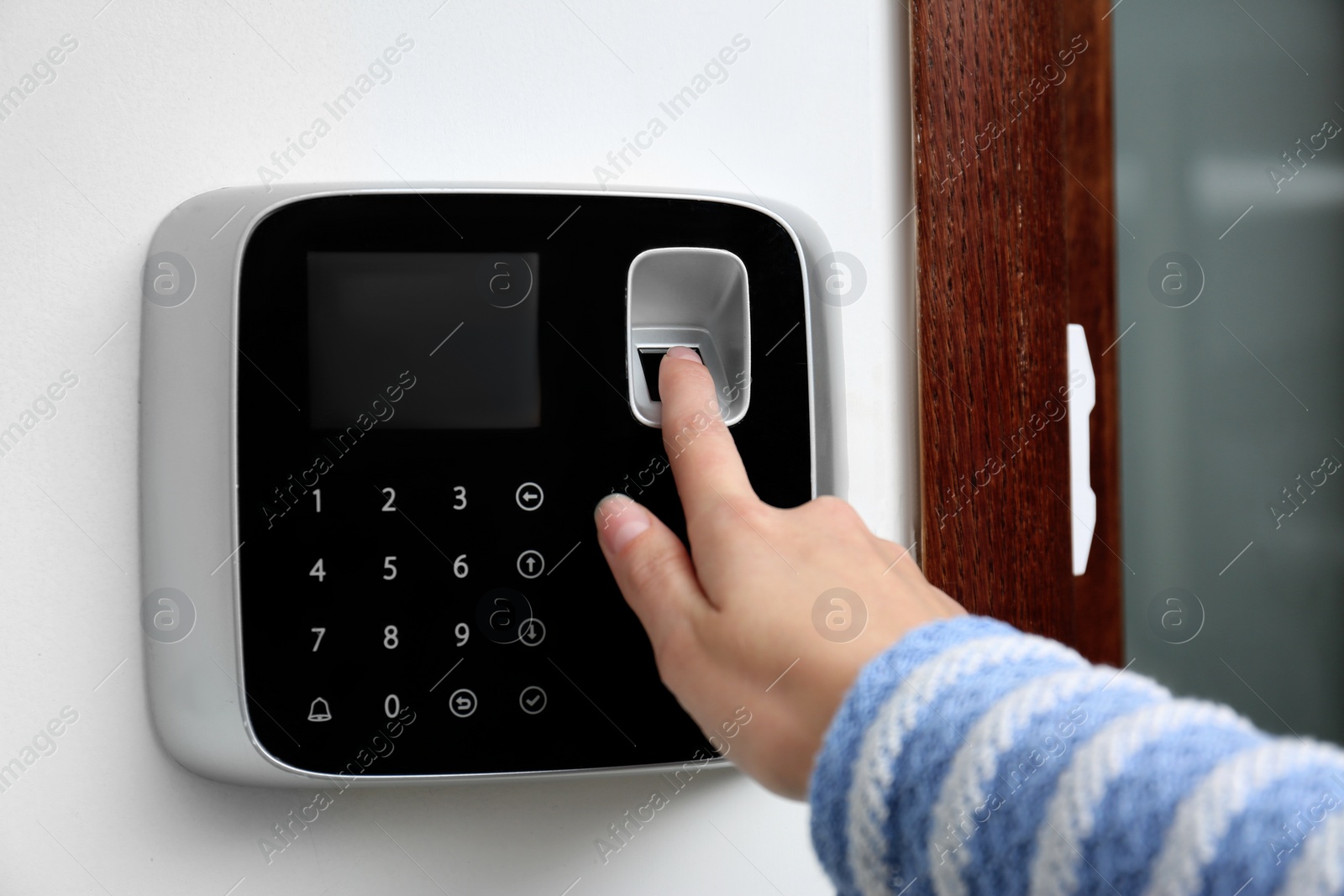 Photo of Woman scanning fingerprint on alarm system indoors, closeup