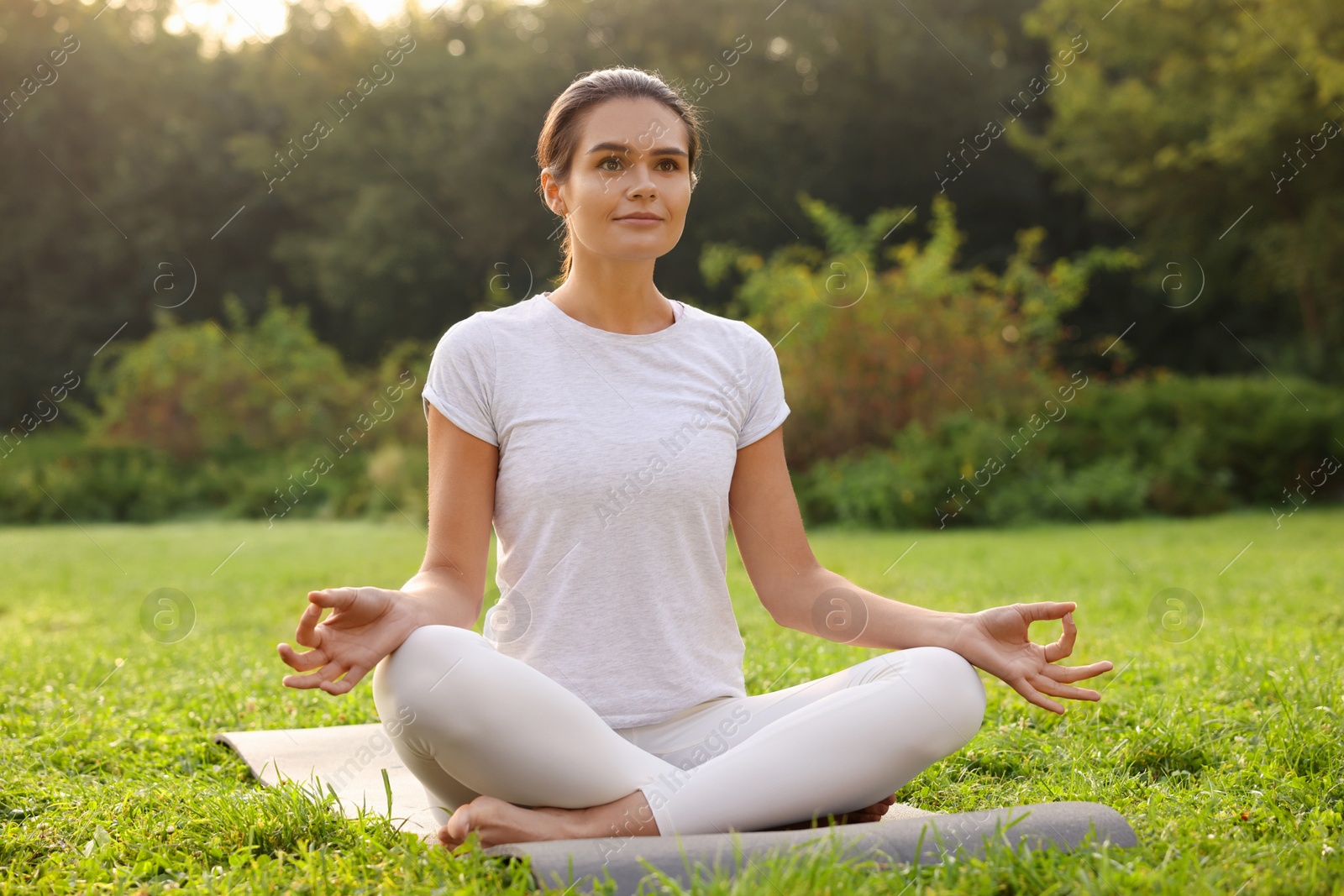 Photo of Beautiful woman practicing yoga on mat outdoors. Lotus pose