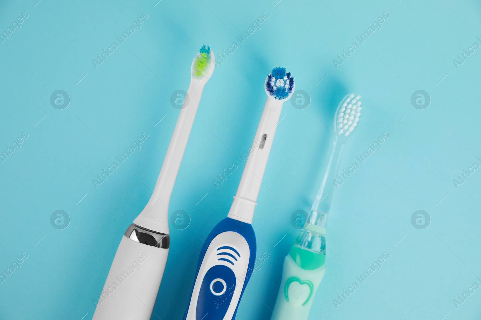 Photo of Electric toothbrushes on light blue background, flat lay