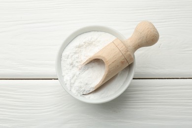 Baking powder in bowl and scoop on white wooden table, top view