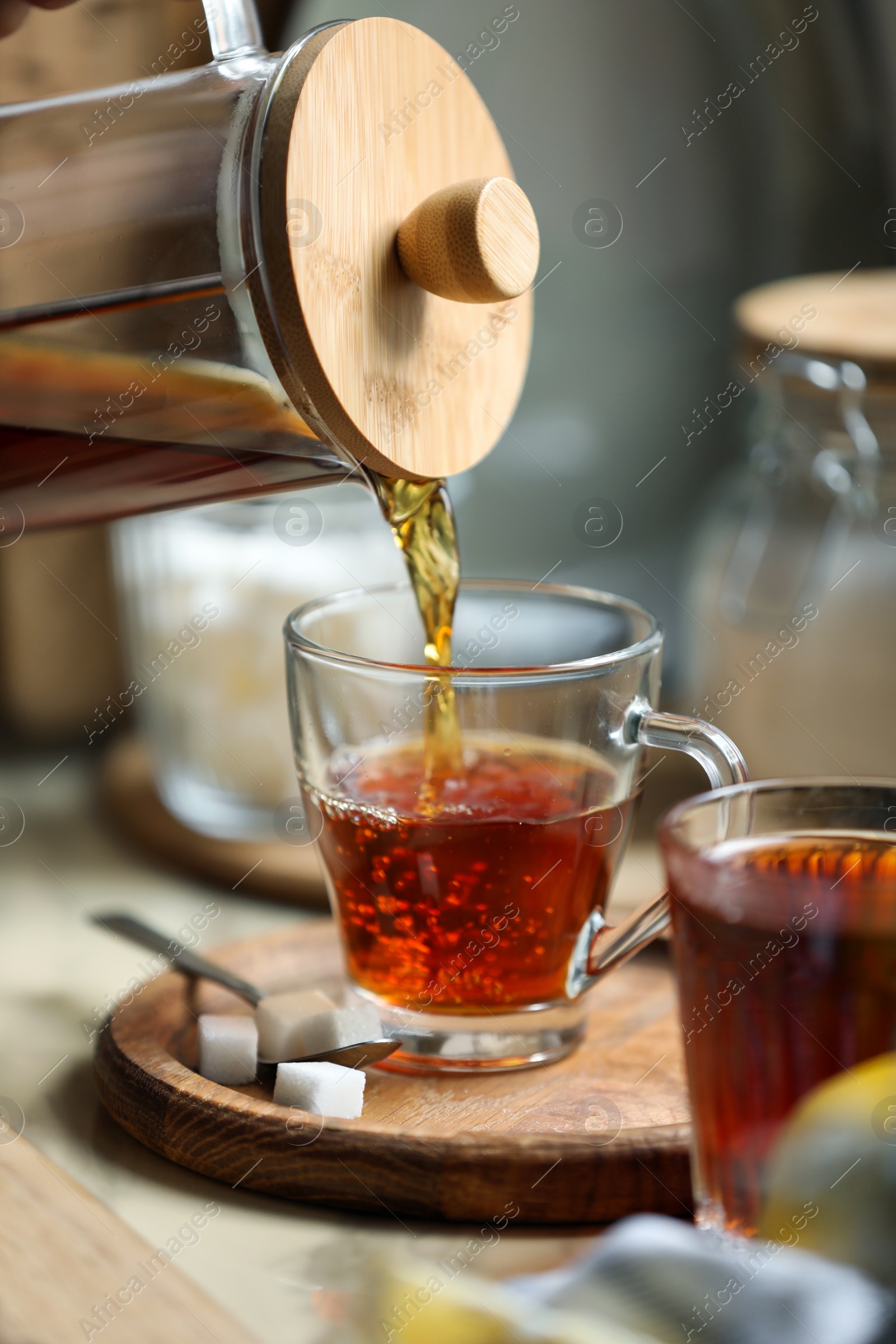 Photo of Pouring delicious tea into glass cup on table, closeup