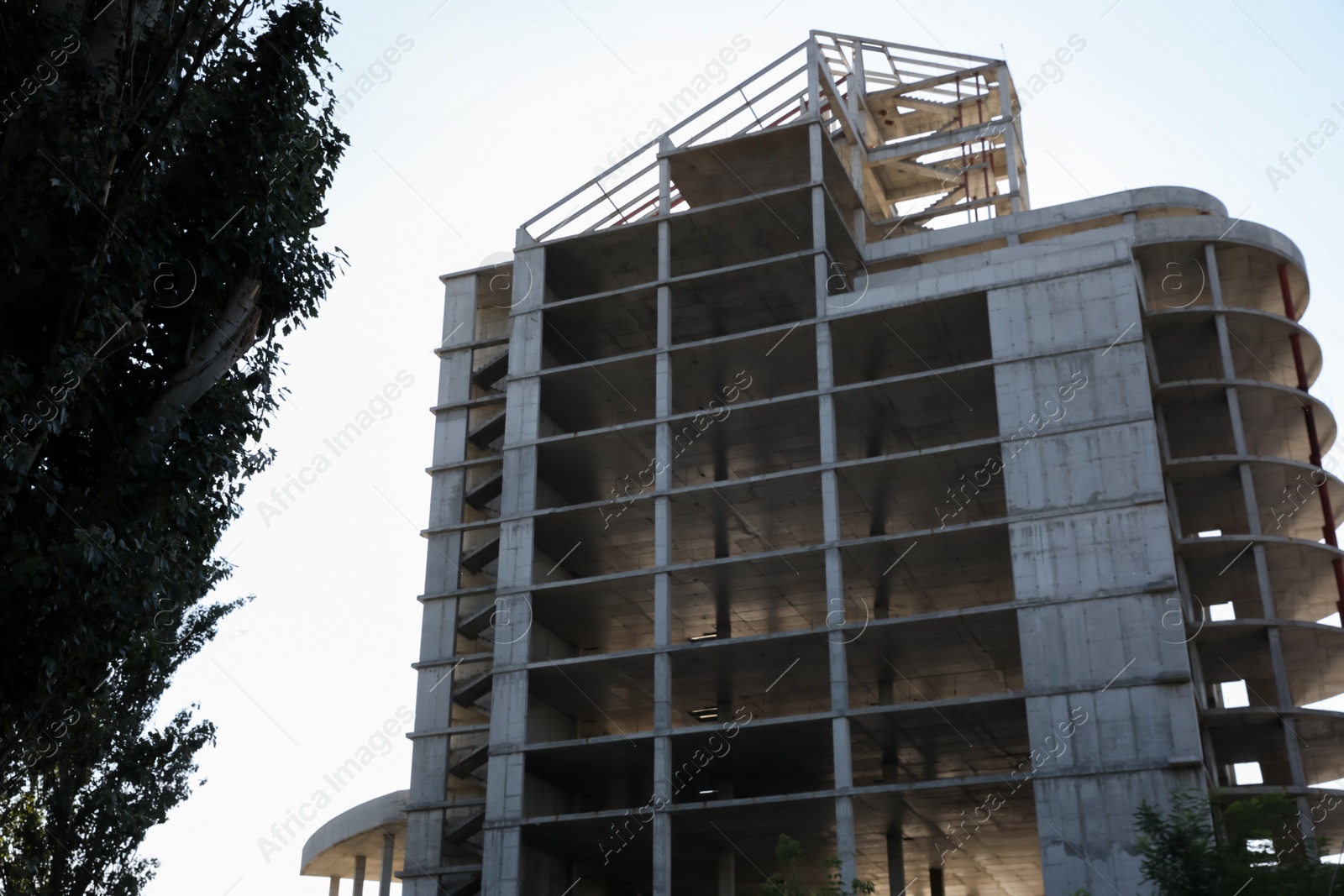 Photo of Unfinished building and green tree outdoors on sunny day