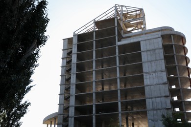 Unfinished building and green tree outdoors on sunny day