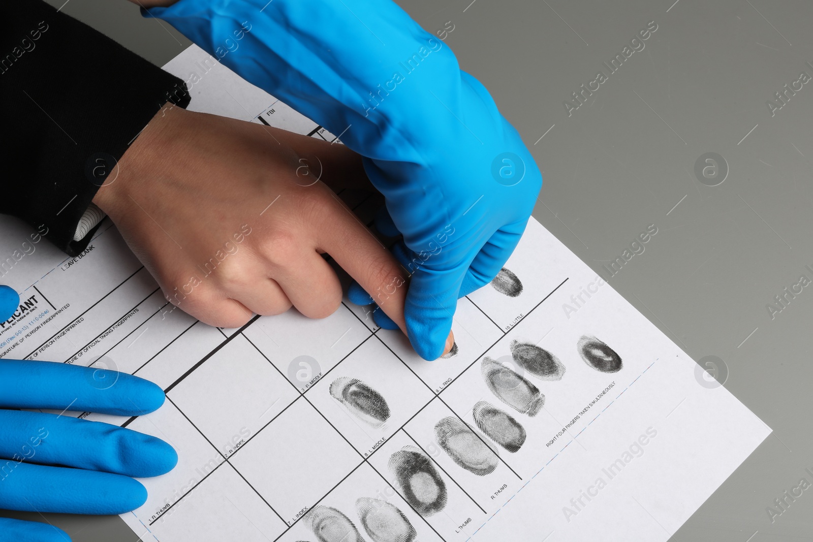 Photo of Investigator taking fingerprints of suspect at table, closeup. Criminal expertise