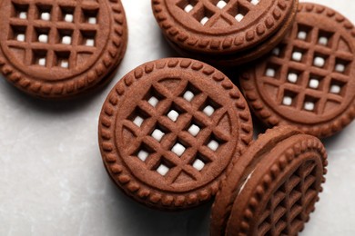 Tasty chocolate sandwich cookies with cream on light grey marble table, flat lay