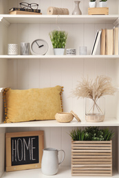 White shelving unit with plants and different decorative stuff