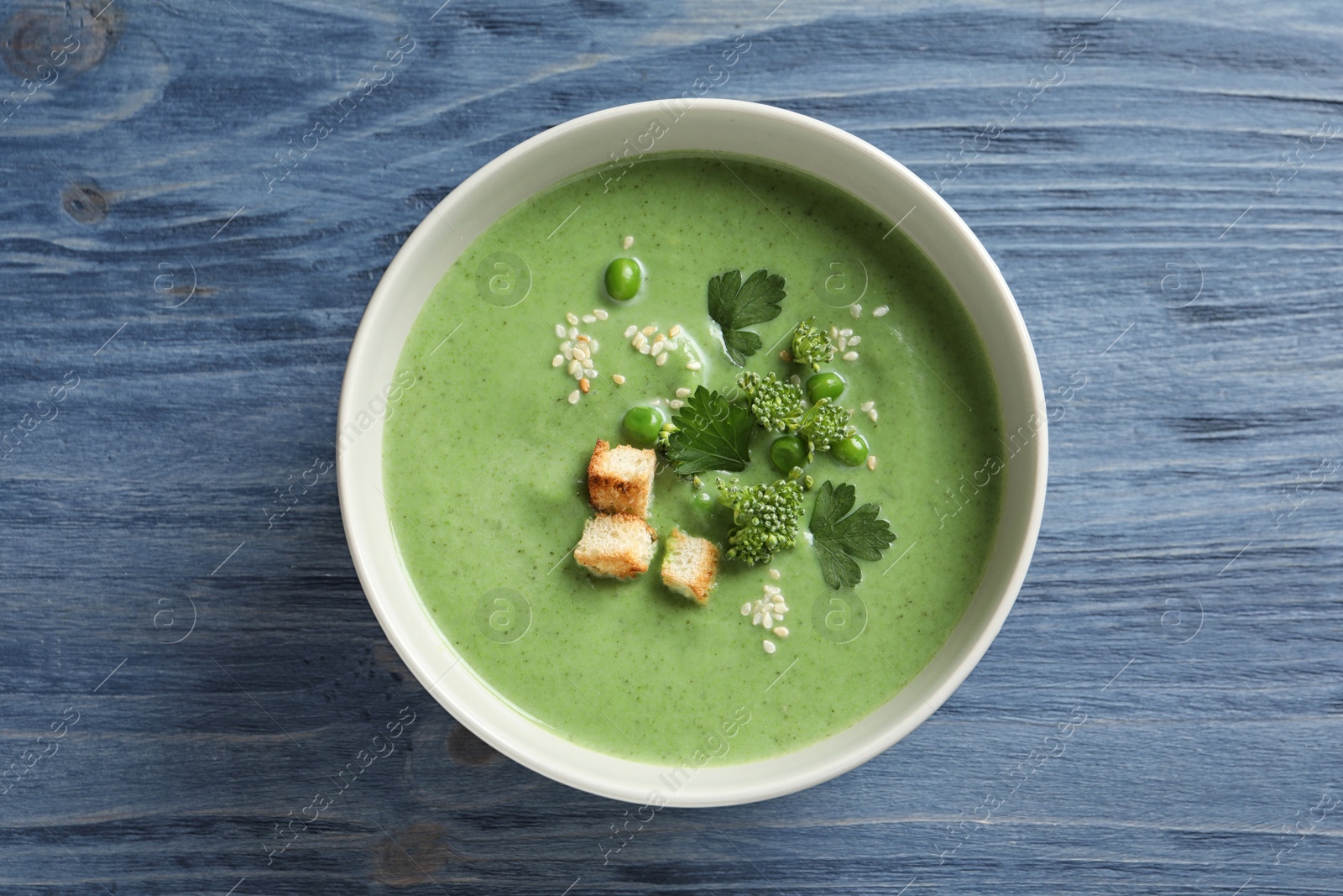 Photo of Fresh vegetable detox soup made of green peas and broccoli in dish on wooden background, top view