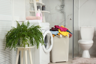 Basket with laundry and washing machine in bathroom