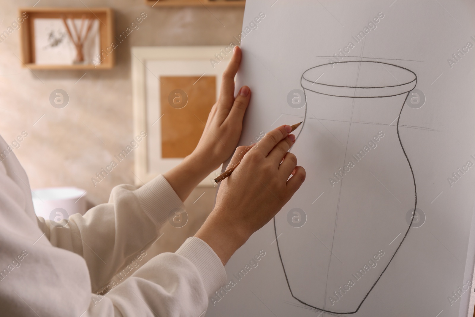 Photo of Woman drawing vase with graphite pencil on canvas indoors, closeup