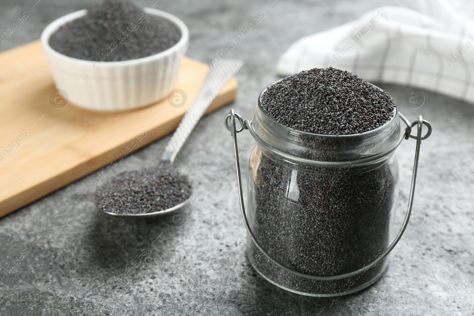 Photo of Poppy seeds in jar on grey table