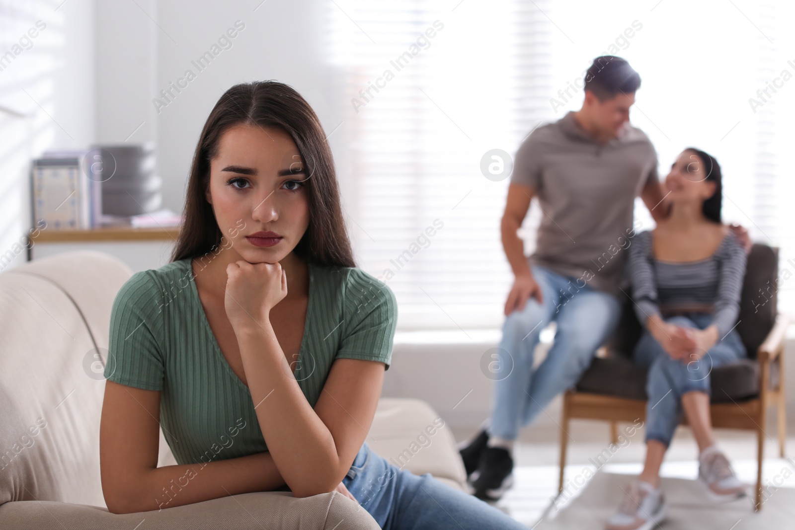 Photo of Unhappy woman feeling jealous while couple spending time together at home